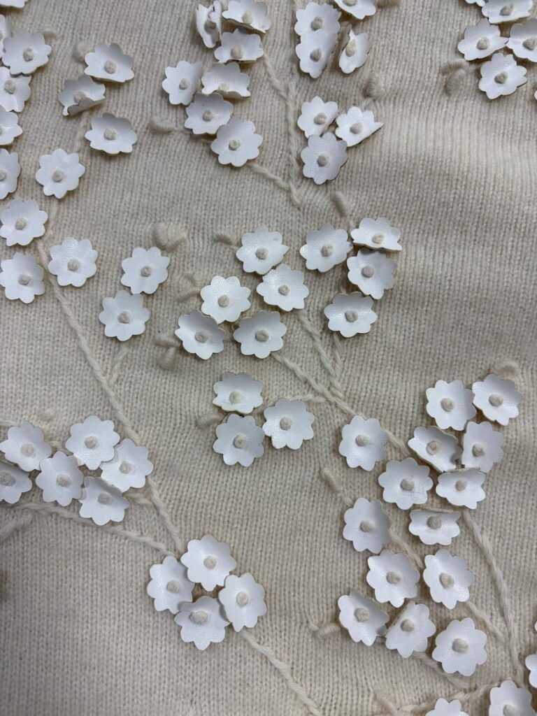 Close-up of 3D floral appliqué on cashmere knit fabric