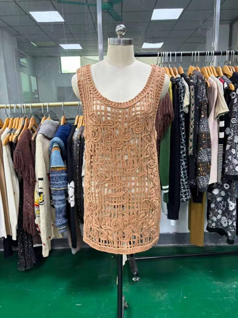 Front view of a beige dress with custom appliqué and cording embroidery.